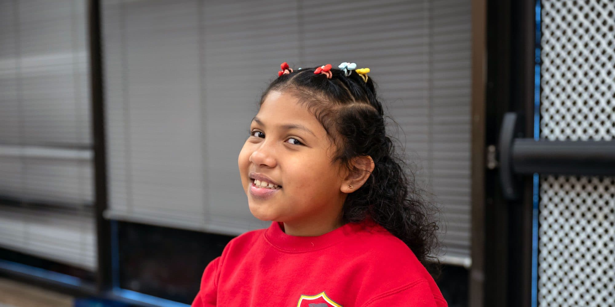 Smiling student with colorful hair clips.